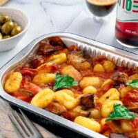 a casserole dish with tomatoes, olives, and meat